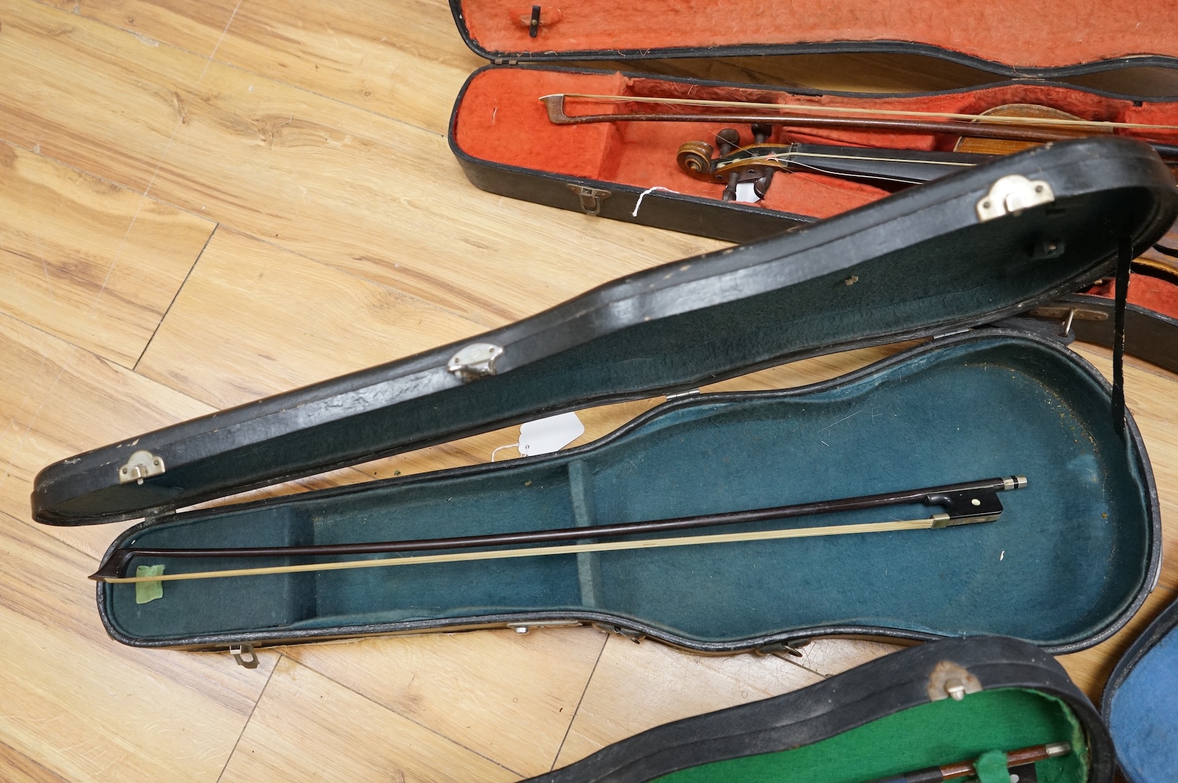 Five cased 20th century violins, including; a German violin, two Czech violins, a three-quarter size violin with a label for Bienfait, and a Romanian quarter size violin, all in cases or the remains of cases.
